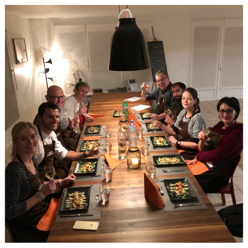 Groupe de convives assis autour d'une table en bois dégustant des plats lors d'un événement culinaire chez Parfum d'Épices