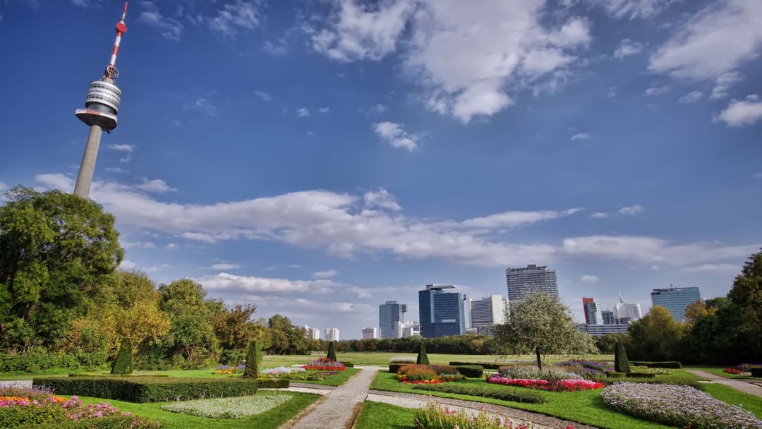 Parc de Vienne avec fleurs colorées, la tour du Danube en arrière-plan et skyline de la ville sous ciel bleu