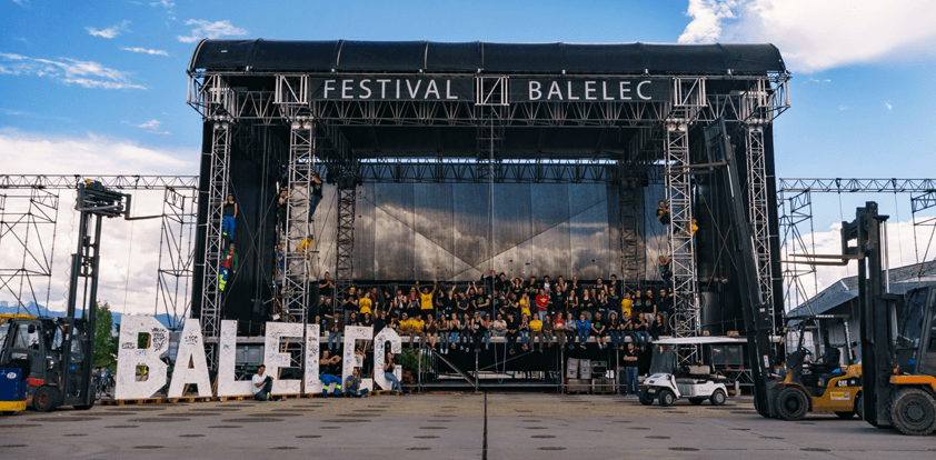 Scène du festival Balélec avec structure métallique imposante, foule sur le plateau et logo géant en blanc au sol