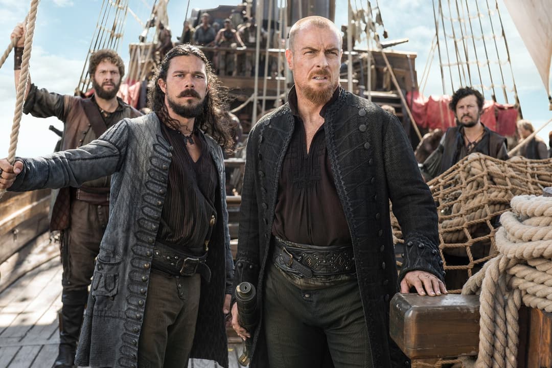 Capitaine Flint et ses compagnons à bord d'un navire pirate, avec cordages et voiles rouges en arrière-plan