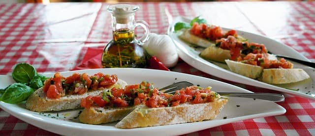 Bruschetta romaine aux tomates et herbes fraîches, huile d'olive et roquette, sur nappe à carreaux rouges et blancs