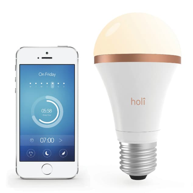 Ampoule connectée Holi blanc et rose gold à côté d'un smartphone affichant une interface de contrôle bleu avec heure de réveil et paramètres de luminothérapie