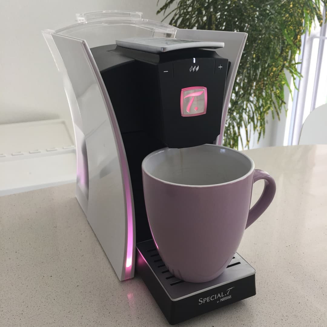 Machine à thé SPECIAL.T de Nestlé aux finitions blanches et noires avec détails roses, accompagnée d'une tasse assortie