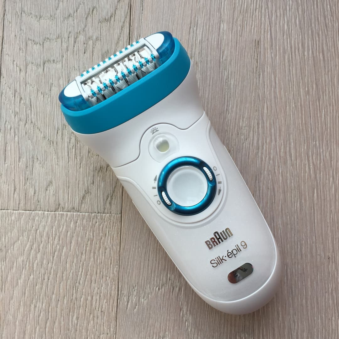 Epilateur Braun Silk-epil 9 blanc et bleu avec tête large sur fond bois