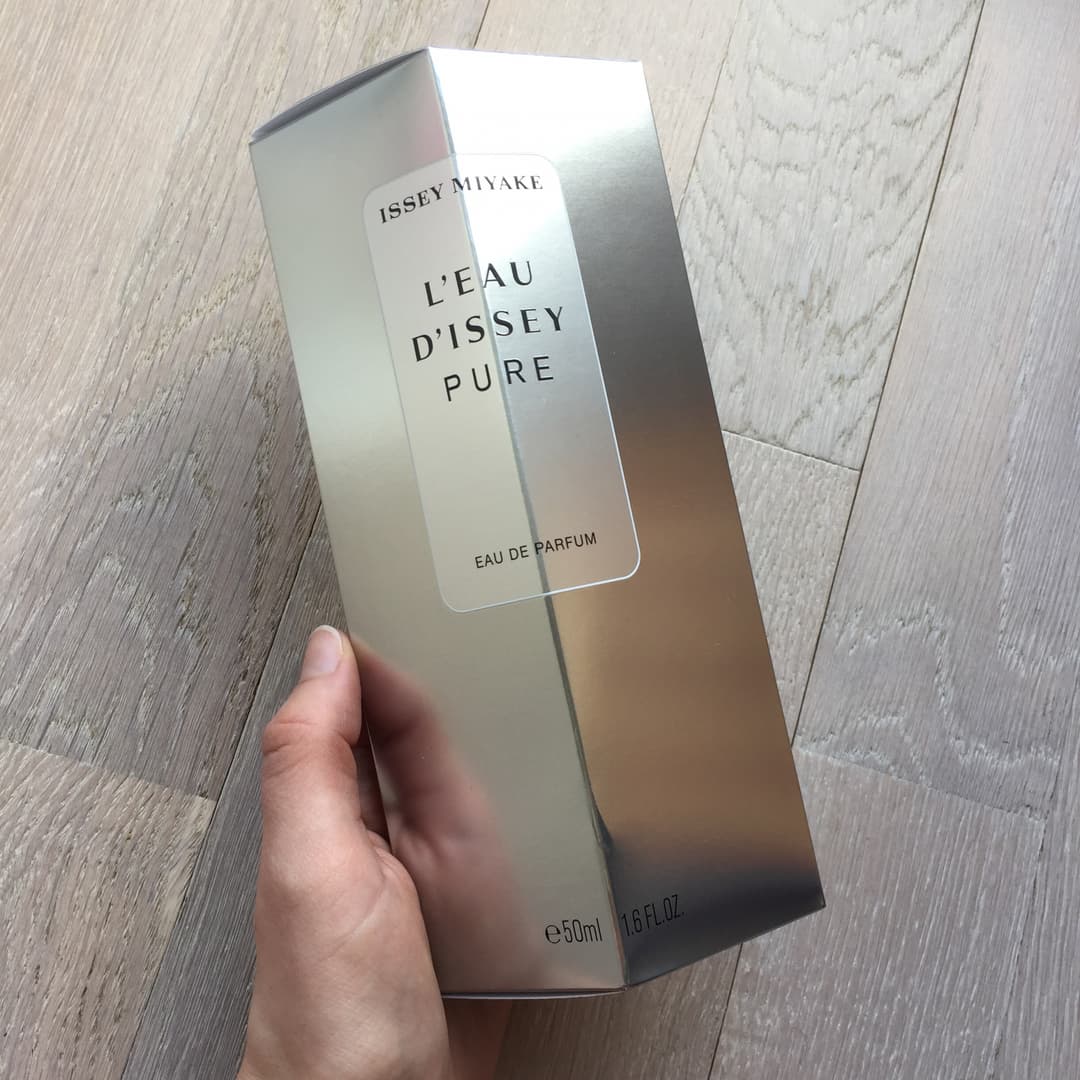 Flacon L'Eau d'Issey Pure d'Issey Miyake 50 ml tenu en main, boîte blanche et grise dégradé