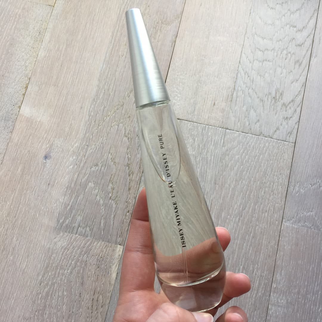 Flacon de l'Eau d'Issey Pure d'Issey Miyake tenu en main, avec bouchon argenté et design épuré en verre transparent