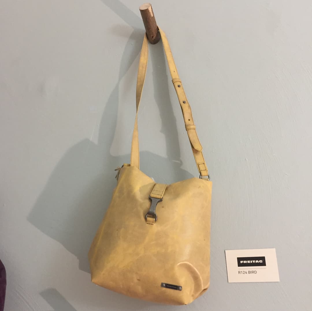 Sac Freitag Bird jaune clair en bandoulière, accroché à une broche murale, avec une étiquette de présentation