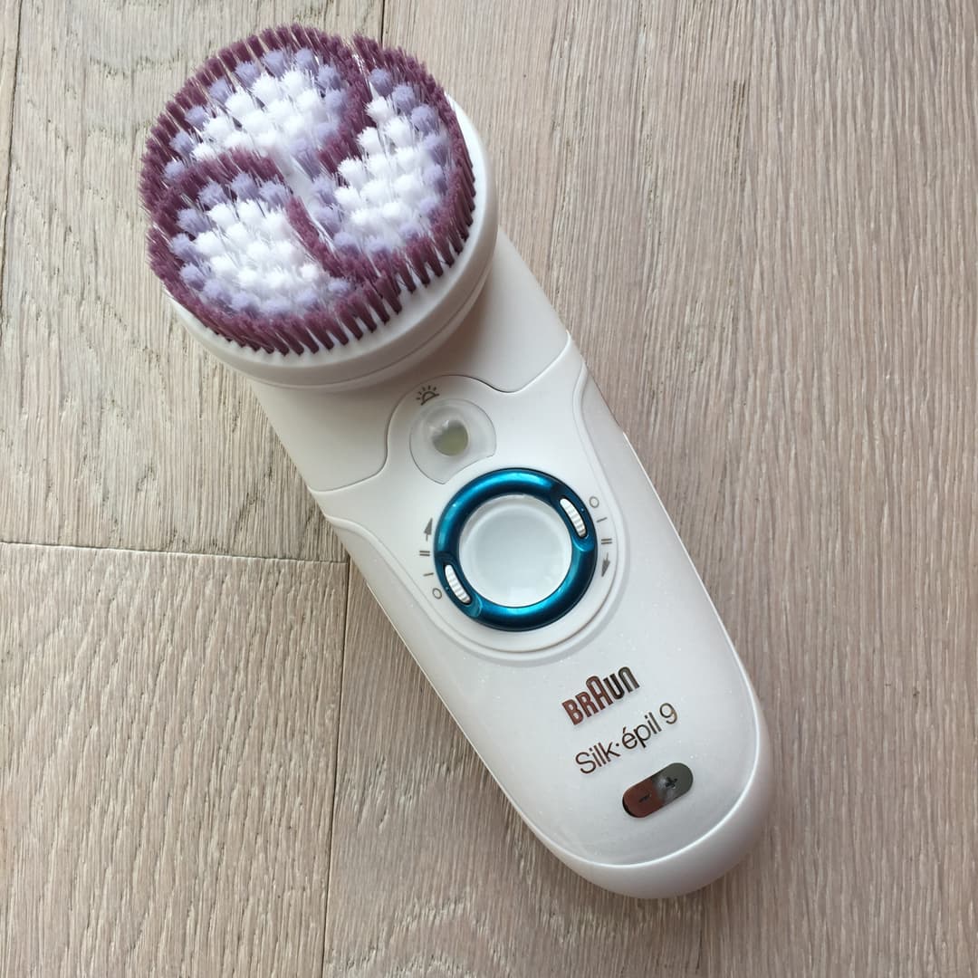 Braun Silk Épil 9 SkinSpa blanc avec tête d'épilation large aux picots violet et blanc, posé sur bois clair