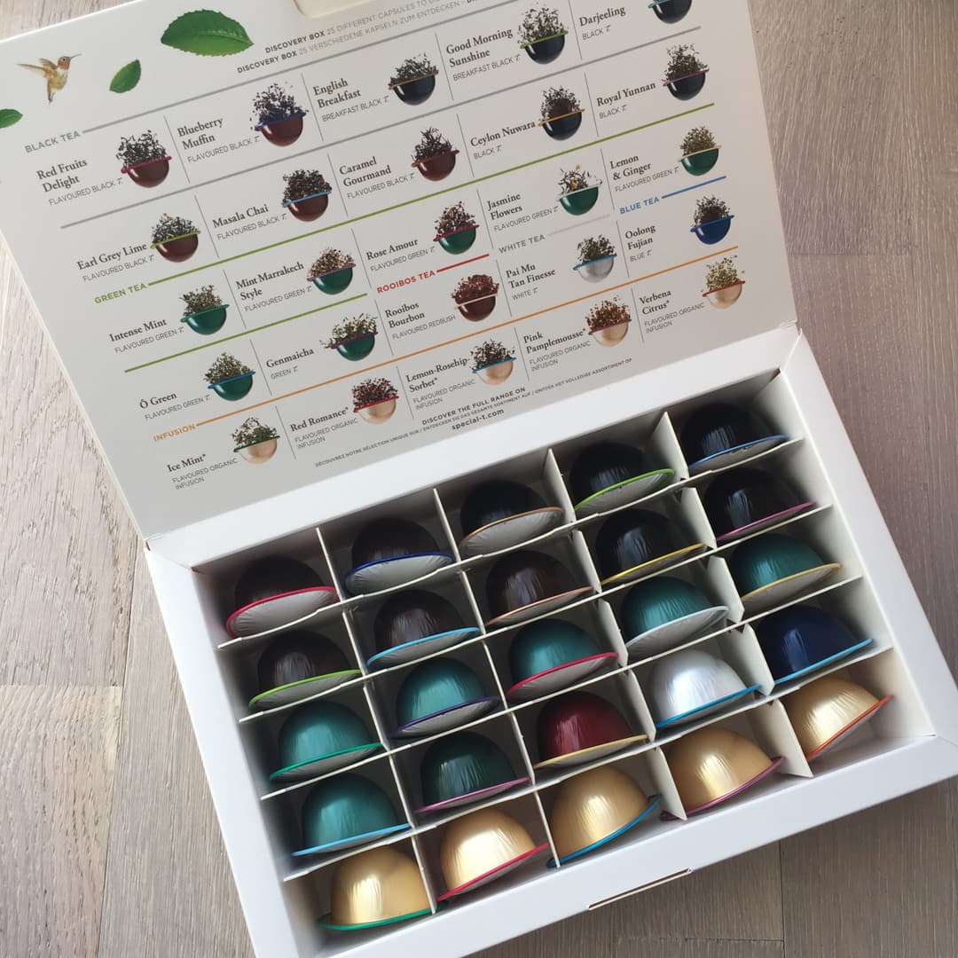 Coffret découverte SPECIAL.T ouvert avec guide des variétés de thé noir, vert, blanc et infusion, et capsules de couleurs variées rangées dans des compartiments