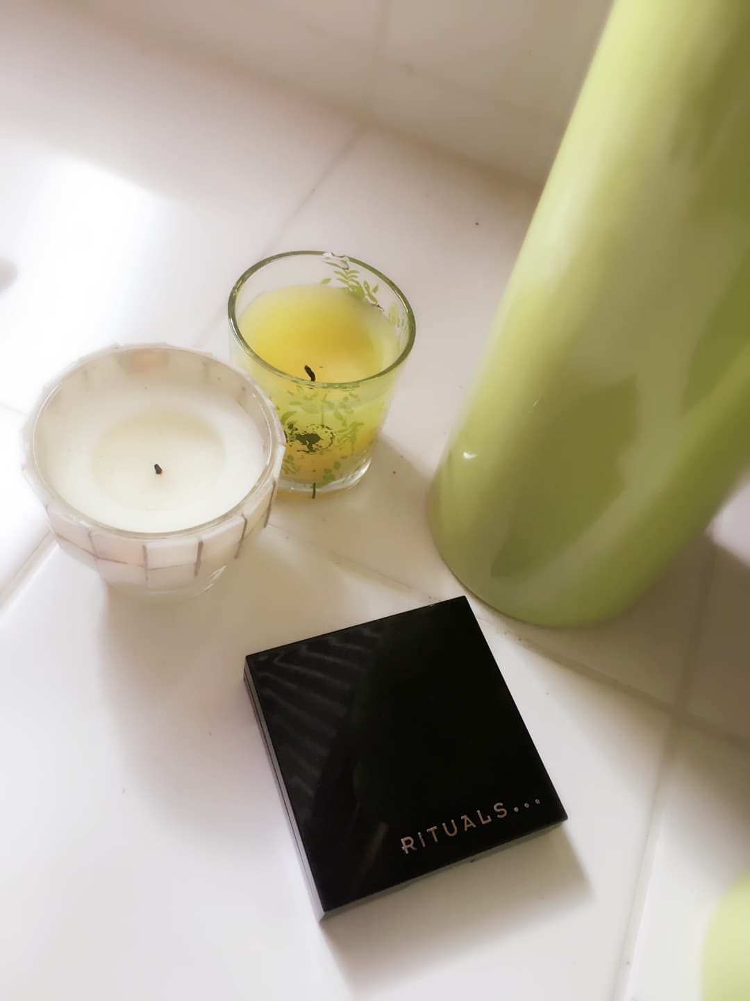 Boîte noire de Magic Powder Blush Ritals, bougie blanche et verre jaune clair avec herbes sur surface blanche