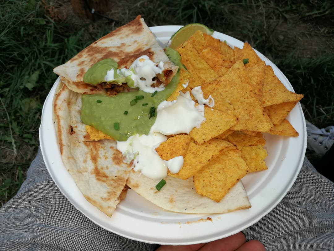 Assiette avec quesadilla au poulet garnie de guacamole et crème fraîche, accompagnée de nachos épicés