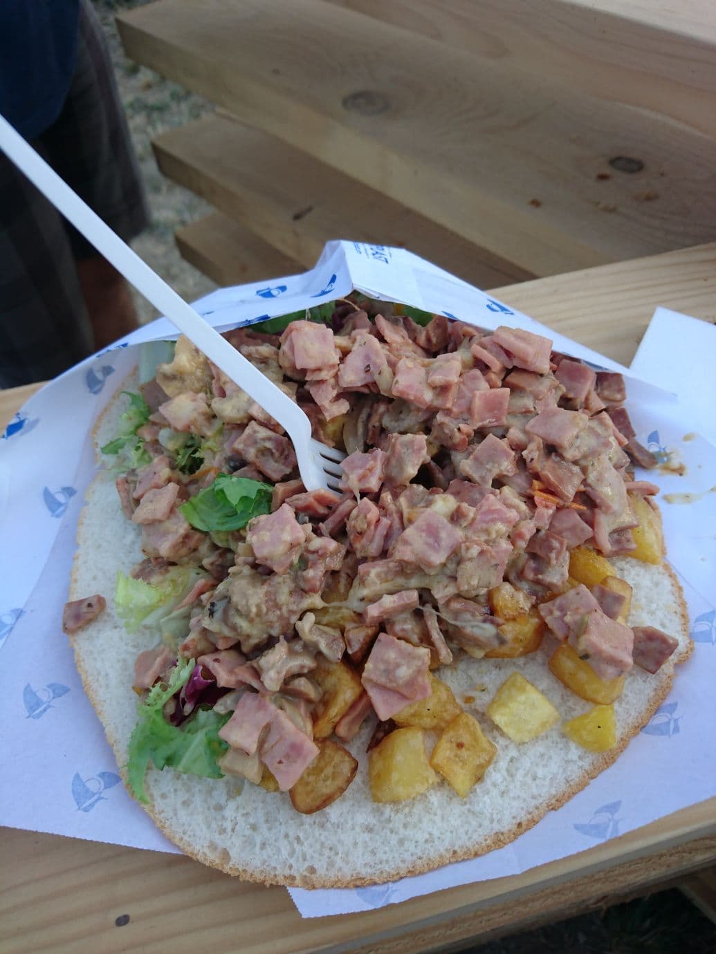 Sandwich corse garni de champignons sautés, pommes de terre en cubes dorés, salade et viande, servi dans une assiette en carton au Paléo Festival