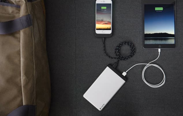 Batterie externe blanche Mophie Powerstation rechargeant un smartphone et une tablette avec câbles noirs et blancs sur fond gris