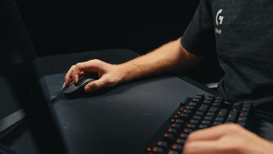 La PRO X SUPERLIGHT 2 DEX en main, sur un tapis de souris, à côté d’un clavier gaming