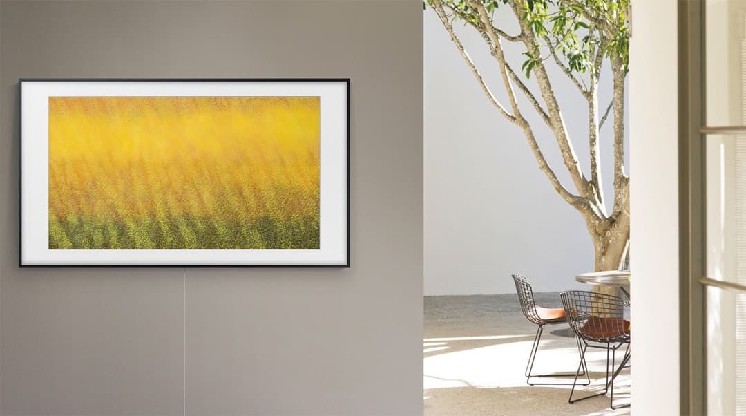 Samsung The Frame 2.0 fixé au mur affichant une peinture d'un champ de tournesols jaunes dans un intérieur minimaliste