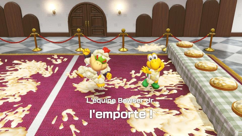 Bowser Jr. et un personnage jaune dansent sur un tapis pourpre jonché de pop-corn dans une salle élégante de Super Mario Party