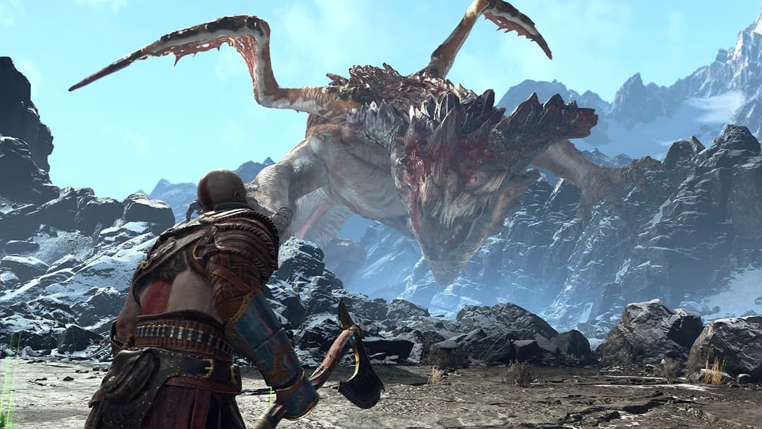 Kratos de dos face à une créature ailée monstrueuse dans un paysage montagneux enneigé du jeu God of War