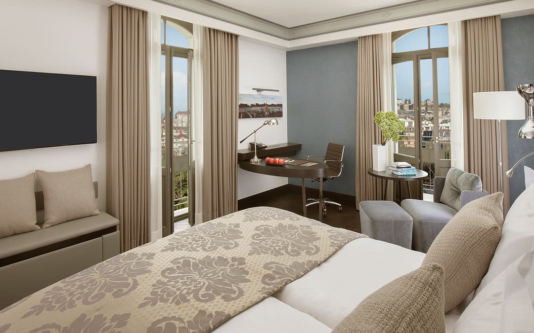 Chambre élégante du Royal Savoy Hotel avec lit double, bureau, balcon donnant sur Lausanne et vue sur la ville