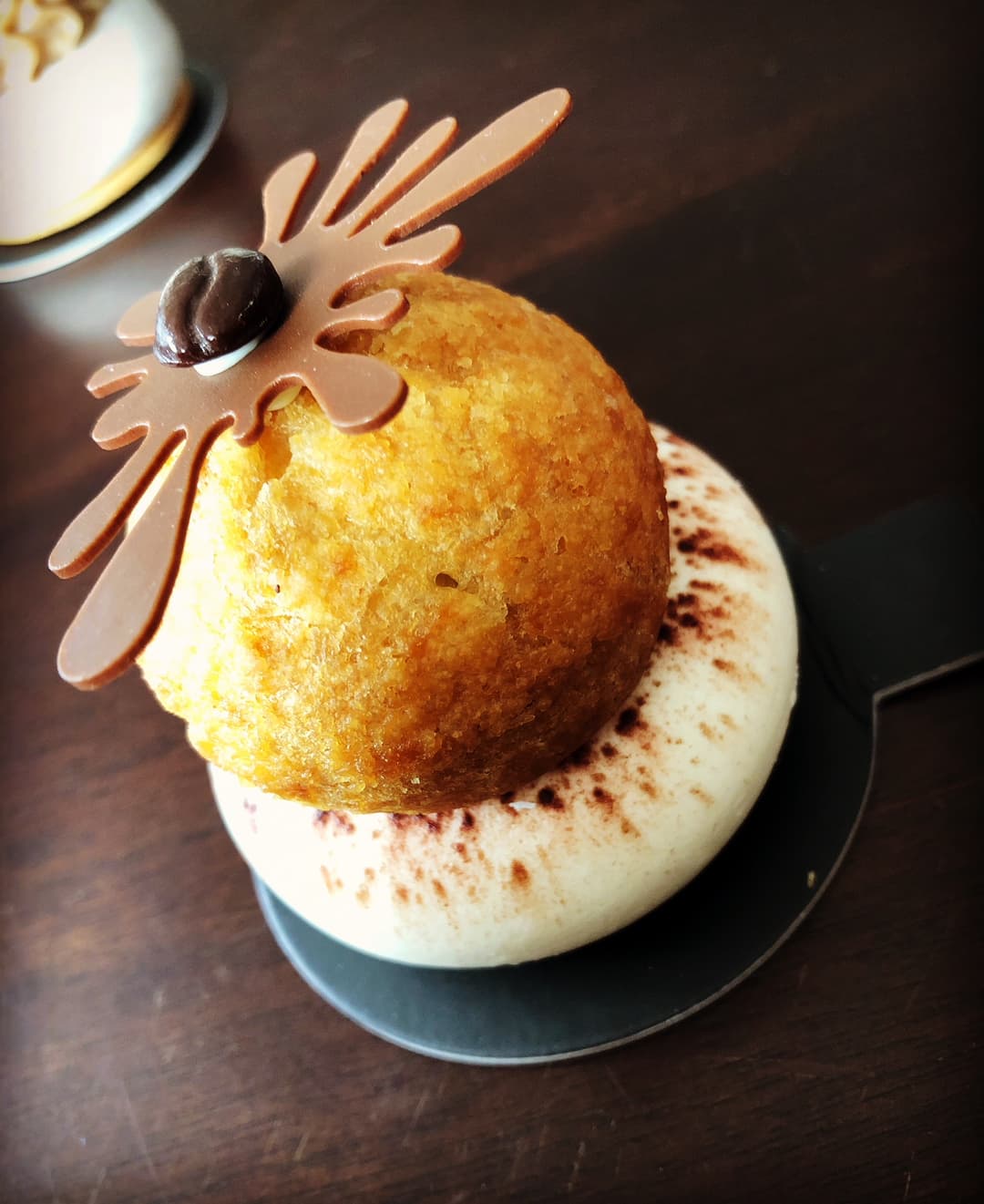 Tiramichou du chef Damien Moutarlier : chou à la pâte dorée reposant sur crème tiramisu poudée de cacao, garni d'une décoration en pâte de caramel