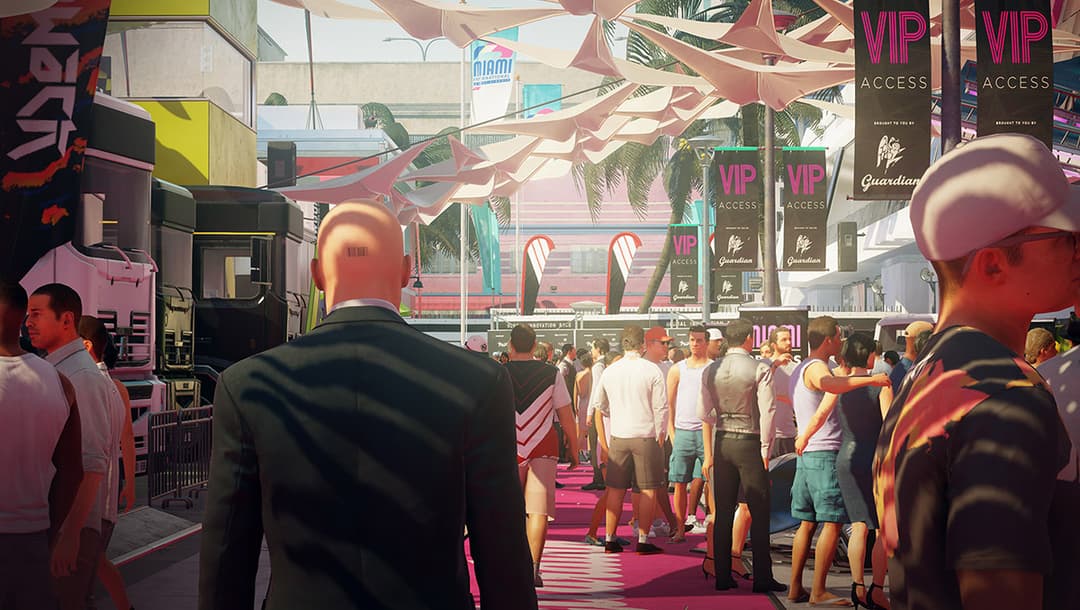 L'agent 47 chauve et vêtu de noir observe une foule dans une zone VIP extérieure avec palmiers et panneaux roses