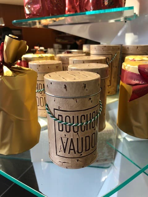 Bouchons de liège estampillés Vaudois, exposés sur une étagère en verre dans l'atelier du chef pâtissier