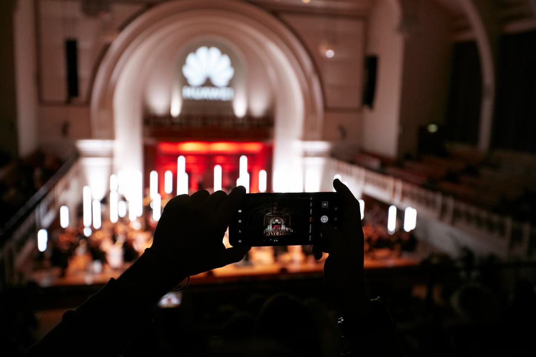 Main tenant un smartphone pour photographier une église avec un autel illuminé de bougies blanches et rouges