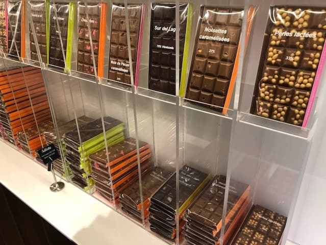 Vitrine de chocolats artisanaux avec barres et pralines dans des emballages aux bandes colorées oranges, vertes et roses