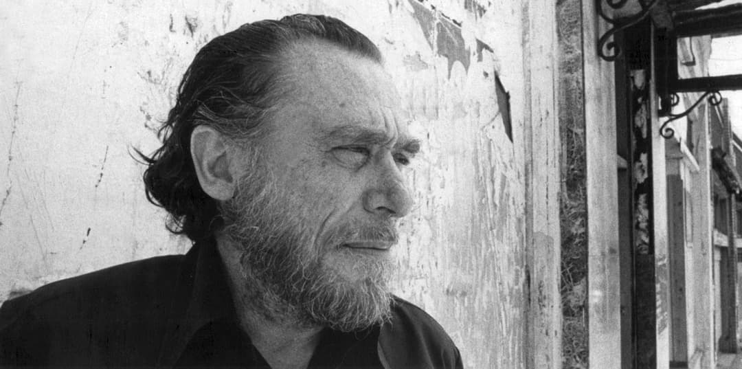 Homme barbu aux cheveux longs, regard pensif, dans une photographie noir et blanc