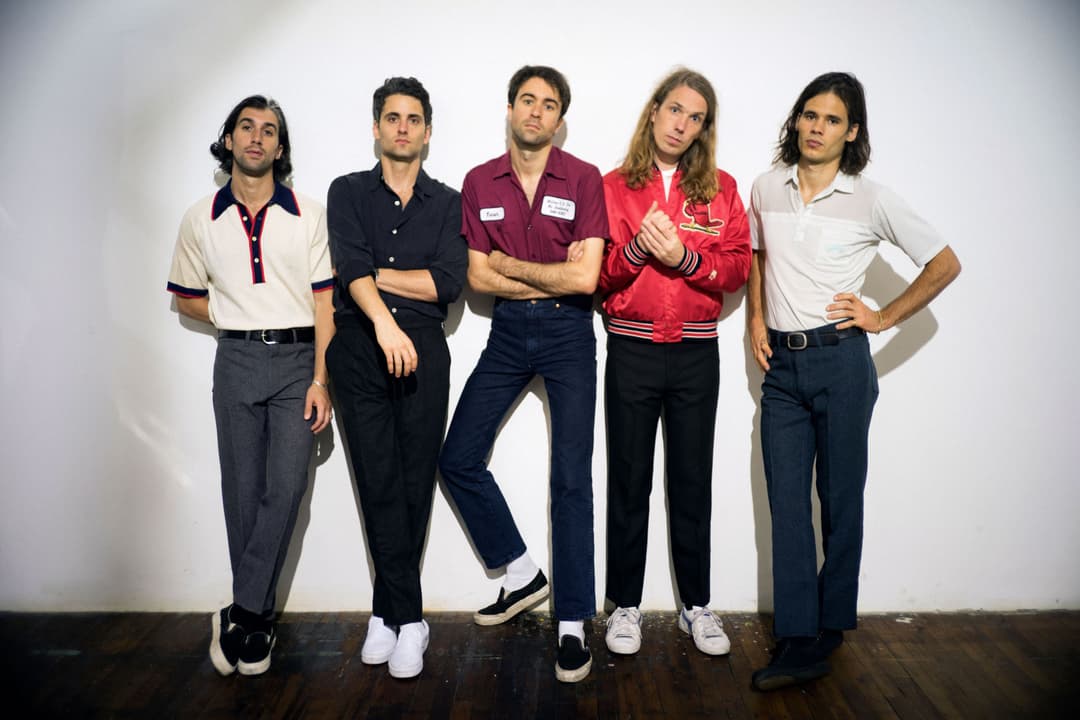 The Vaccines, groupe de rock britannique composé de cinq musiciens alignés face à l'appareil photo en tenue vintage colorée