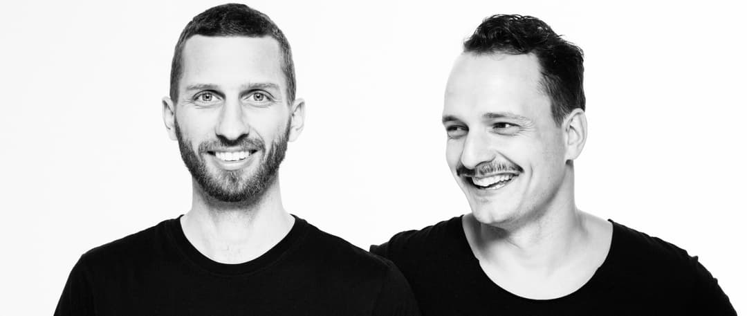 Portrait en noir et blanc de deux hommes souriants, membres du groupe De Staat