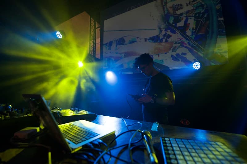 Musicien en silhouette derrière un clavier lors d'un concert avec éclairages jaune et bleu intenses