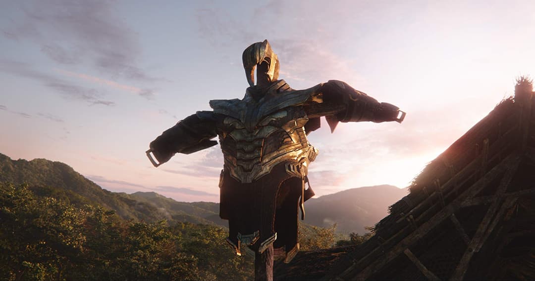 Thanos en armure dorée et noire, bras écartés, debout sur une montagne au coucher du soleil