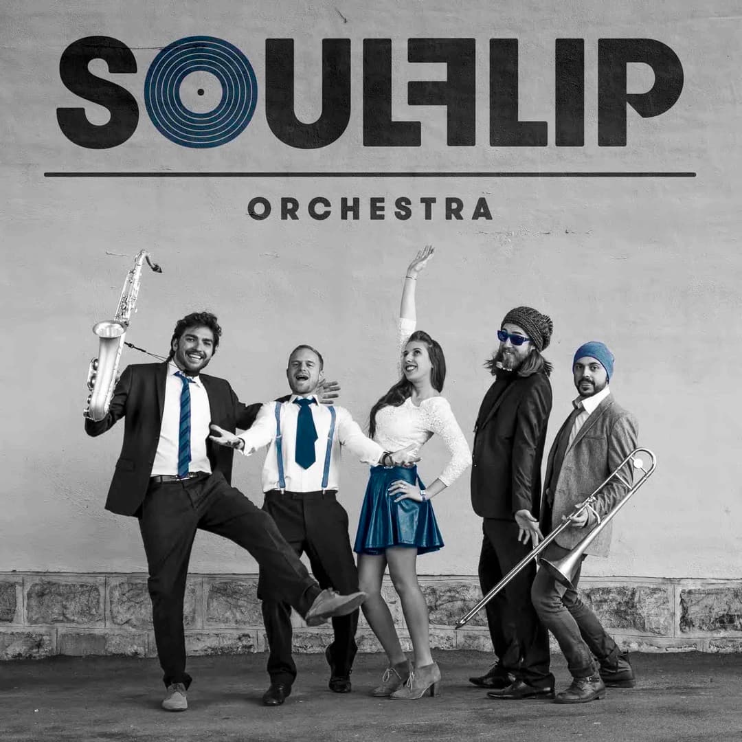 Soulflip Orchestra, cinq musiciens en tenue de scène jouant du saxophone et du trombone devant un mur gris