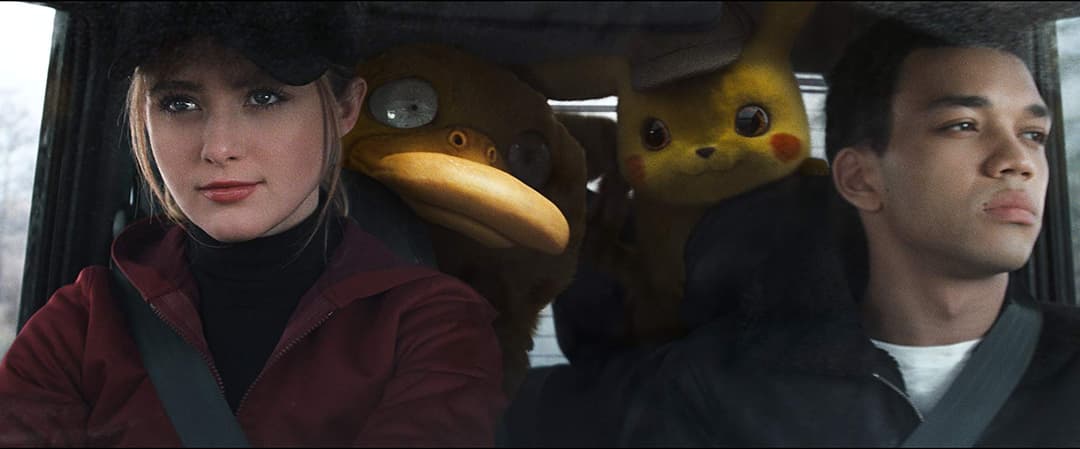 Trois passagers dans une voiture : une femme en veste rouge à gauche, Pikachu au centre et un homme à droite