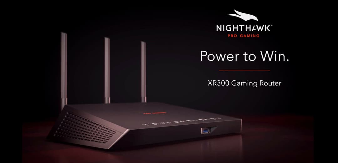 Router Nighthawk XR300 gaming noir avec trois antennes, sur fond sombre avec éclairage rouge