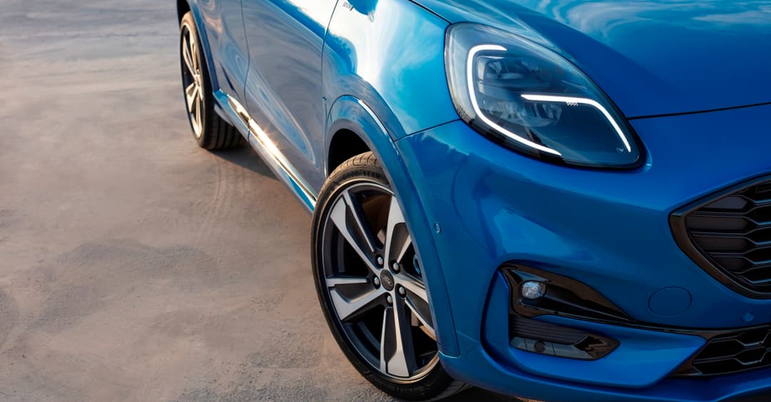 Ford Puma bleu de profil, trois-quarts avant, avec phares LED et jantes alliage, sur fond neutre