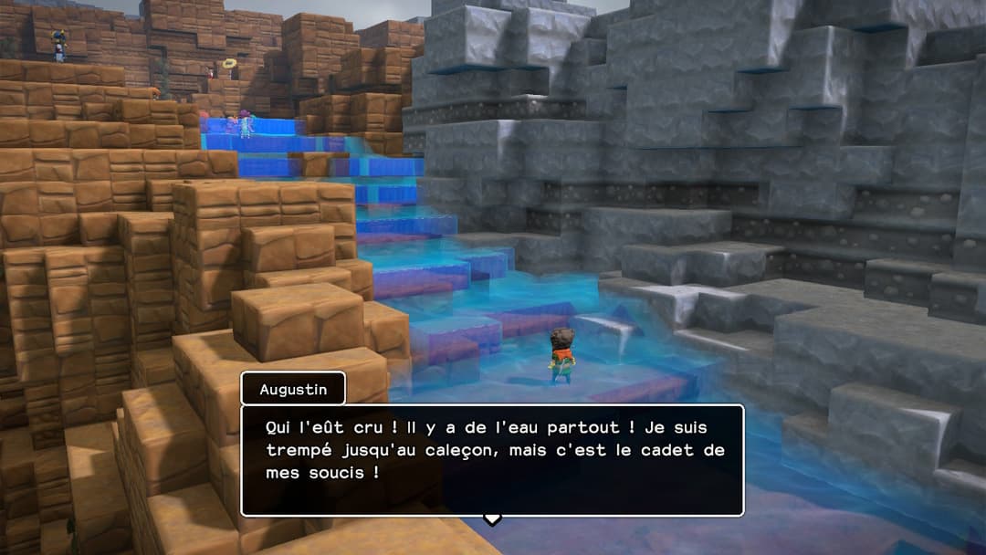 Dragon Quest Builders 2 : personnage debout face à un escalier d'eau bleue entouré de briques de bois et pierre grise
