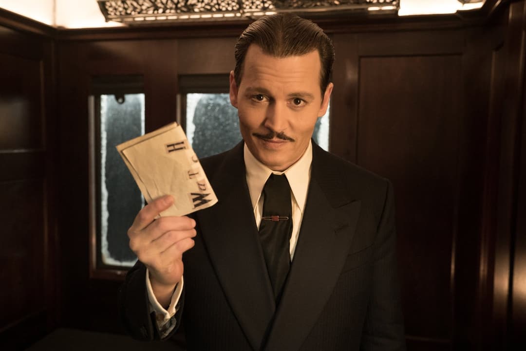 Kenneth Branagh en Hercule Poirot, costume noir et moustache, tenant un carnet dans un wagon du Crime de l'Orient-Express
