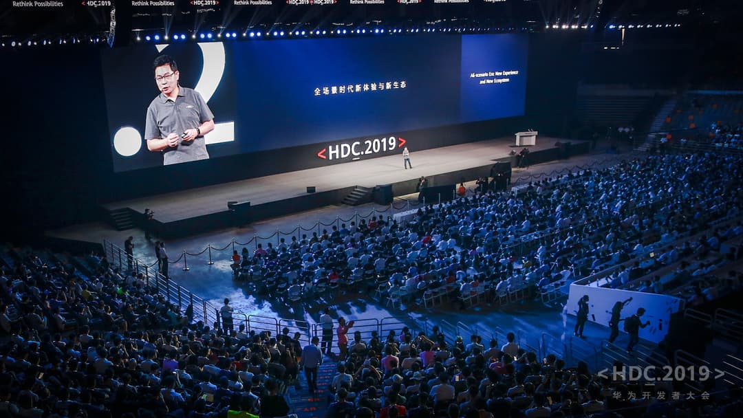 Présentateur sur scène à la conférence Huawei Developer Conference 2019, devant un grand écran bleu et une salle comble