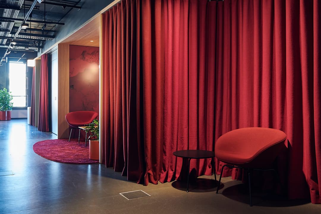 Intérieur moderne du siège Google Suisse à Zurich, avec rideaux rouges, chaises design rouges et éclairage contemporain