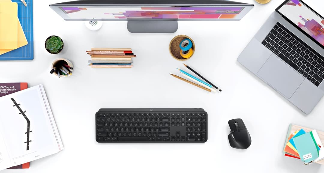 Clavier MX Keys noir et souris MX Master 3 noire de Logitech sur un bureau avec ordinateur portable et accessoires de travail