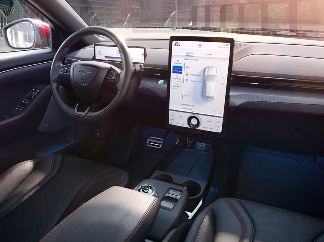 Intérieur de la Ford Mustang Mach-E GT avec volant, écran tactile affichant les paramètres de la voiture électrique et sièges sportifs