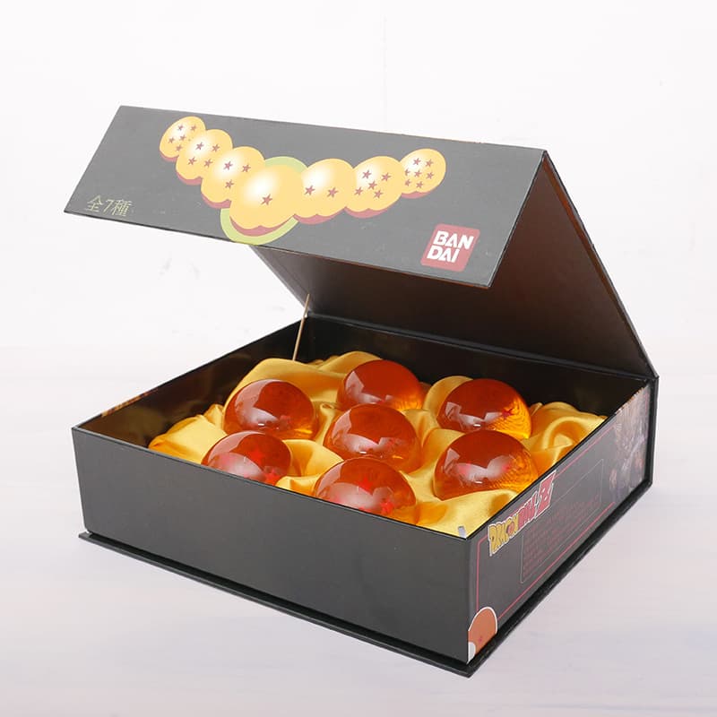 Boîte grise Bandai ouverte contenant sept boules de cristal Dragon Ball orange et rouges avec étoiles noires