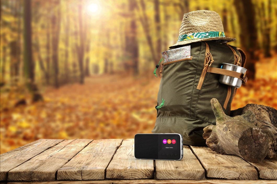 Radio portable PURE Move T4 noire avec affichage coloré, posée sur une table en bois en forêt d'automne