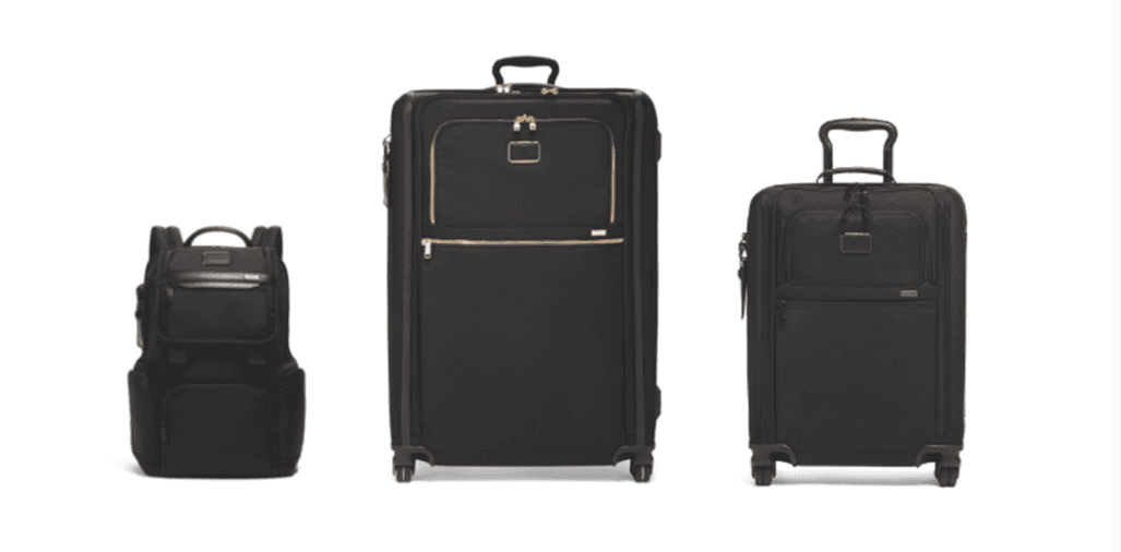 Trois bagages TUMI noirs : un sac à dos, une valise trolley grande avec détails dorés et une valise trolley medium