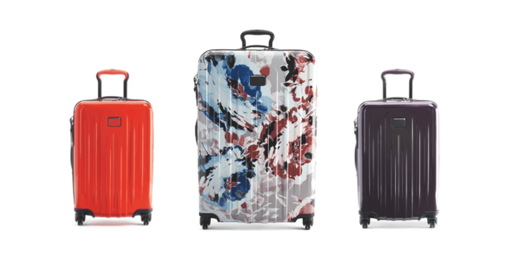 Trois valises TUMI V4 : une rouge Bright Red, une centrale aux motifs floraux bleus et rouges Blush Floral, une prune Blackberry