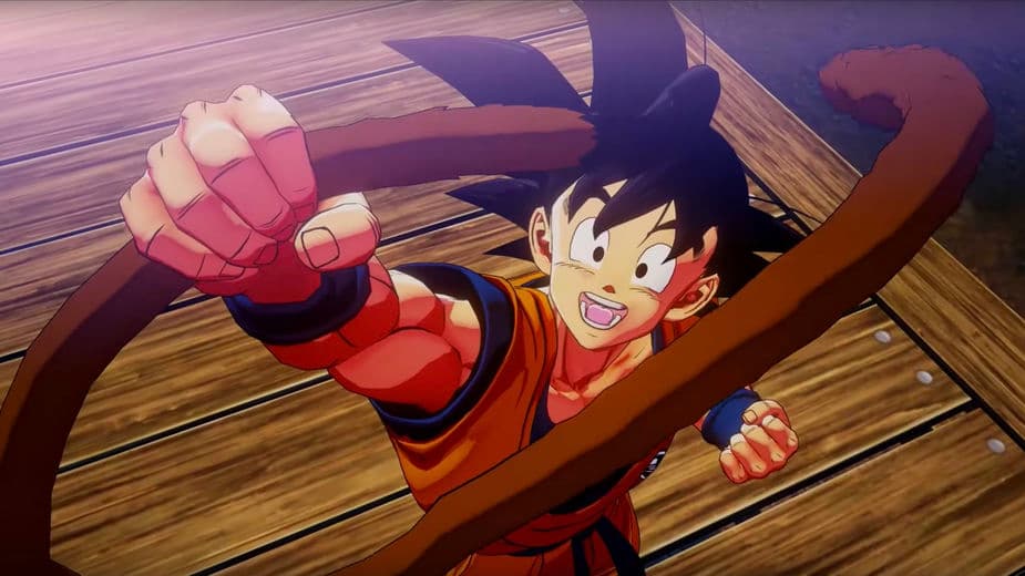 Goku en tenue rouge et bleue, souriant et combat sur un ring en bois dans Dragon Ball Z Kakarot