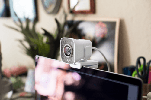 Caméra Logitech StreamCam blanche fixée sur le bord d'un écran dans un bureau