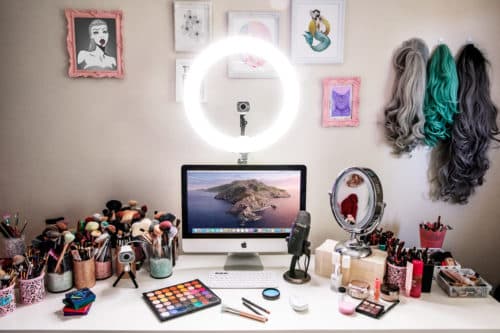 Caméra Logitech StreamCam noire montée sur un bras articulé, installée sur un bureau de créateur avec ring light, ordinateur et accessoires de maquillage