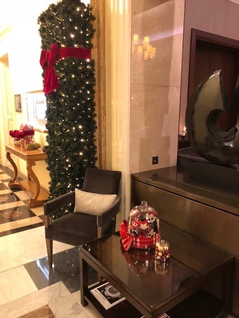 Entrée du Beau-Rivage Palace décorée de sapins illuminés avec nœuds rouges et ornements festifs